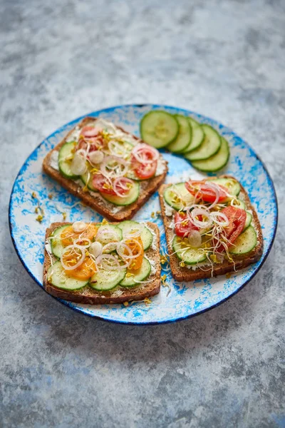 Prato com torradas com pepino, tomate e feta desintegrado e brotos de rabanete — Fotografia de Stock