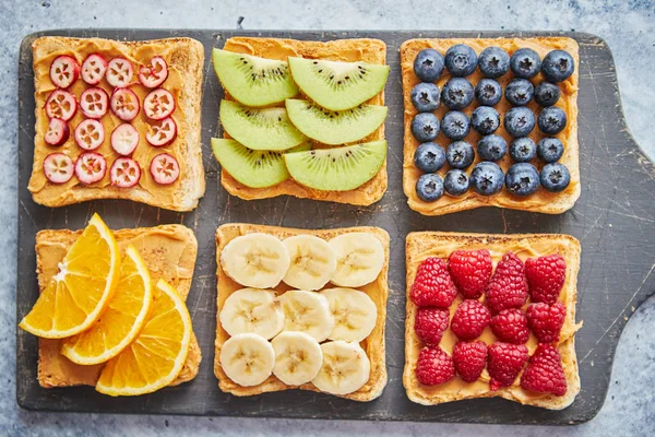 Кусочки хлеба с арахисовым маслом и различными фруктами — стоковое фото