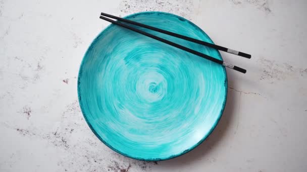 Бирюзовая керамическая покрашенная вручную тарелка с деревянными палочками на боку — стоковое видео