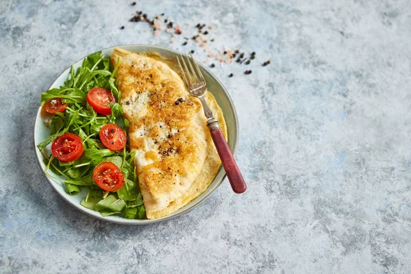 Omelette aux œufs classique servie avec salade de tomates cerises et roquette sur le côté — Photo