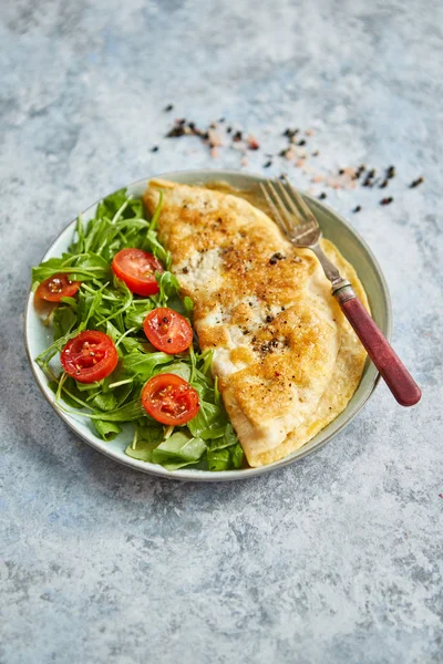 Omelette aux œufs classique servie avec salade de tomates cerises et roquette sur le côté — Photo