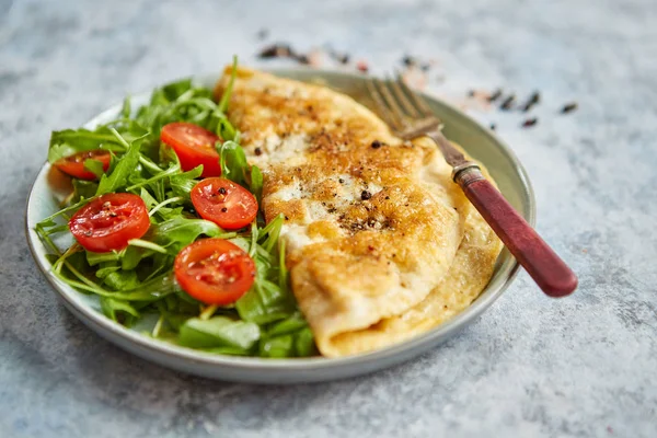 Classic egg omelette served with cherry tomato and arugula salad on side — Stock Photo, Image