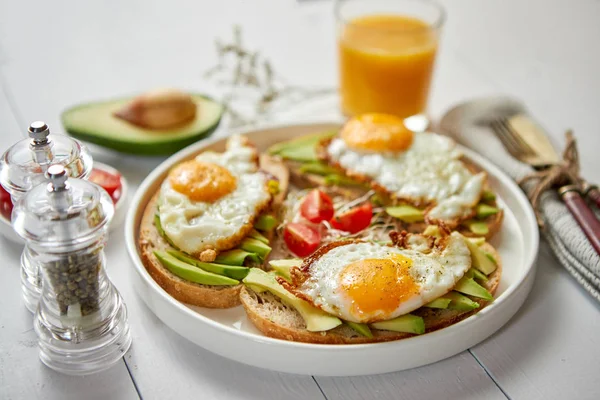 Dilimlenmiş avokado sandviçi ve kızarmış yumurta ile lezzetli sağlıklı bir kahvaltı. — Stok fotoğraf