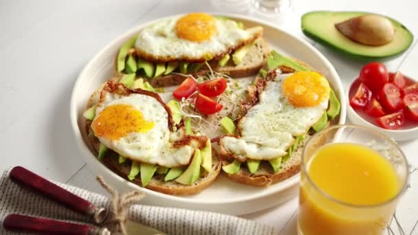 Вкусный здоровый завтрак с нарезанными бутербродами с авокадо и жареным яйцом — стоковое видео