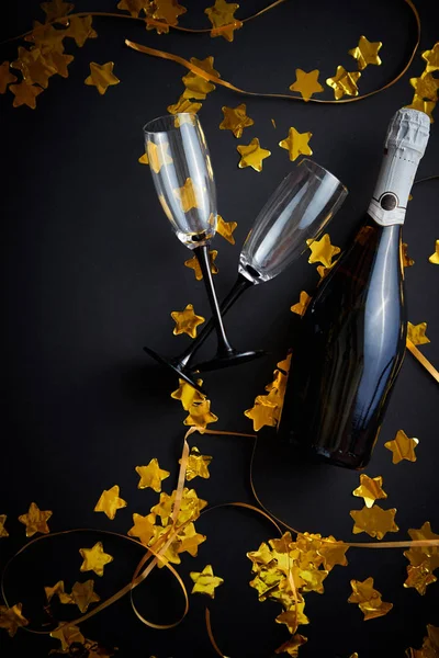 シャンパンのグラスとボトルに黄金のサーペンタインとコンフェッティ — ストック写真