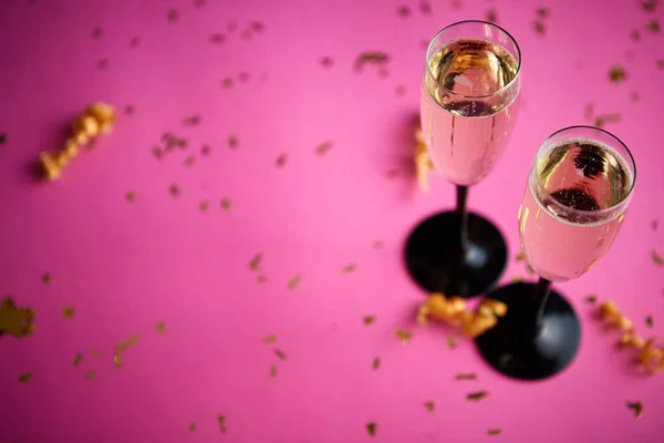 ピンクの背景にコンフェッティとサーペンタインの黄金の装飾が施された輝くシャンパンワインでいっぱいの2つのグラス コピースペース付きのトップビュー 祭りやパーティーのコンセプト — ストック写真