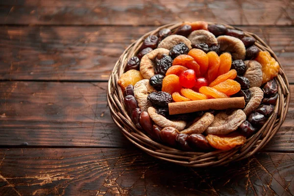 Mélange de fruits secs dans un petit panier en osier sur une table en bois — Photo