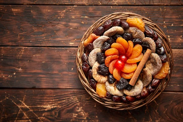 Mélange de fruits secs dans un petit panier en osier sur une table en bois — Photo