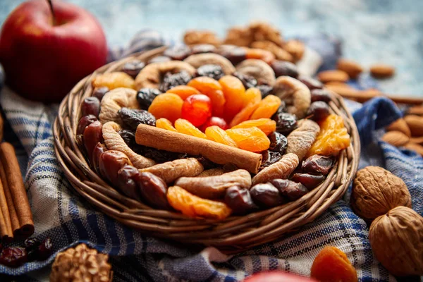 Samenstelling van gedroogde vruchten en noten in kleine rieten schaal geplaatst op stenen tafel — Stockfoto