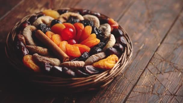 Mix of dried fruits in a small wicker basket on wooden table — Stock Video