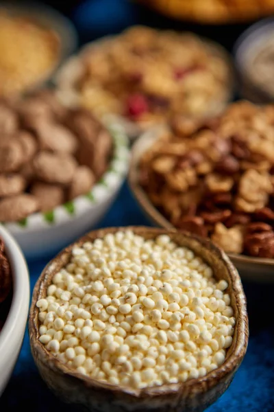 Surtido de diferentes tipos de cereales colocados en cuencos de cerámica en la mesa — Foto de Stock