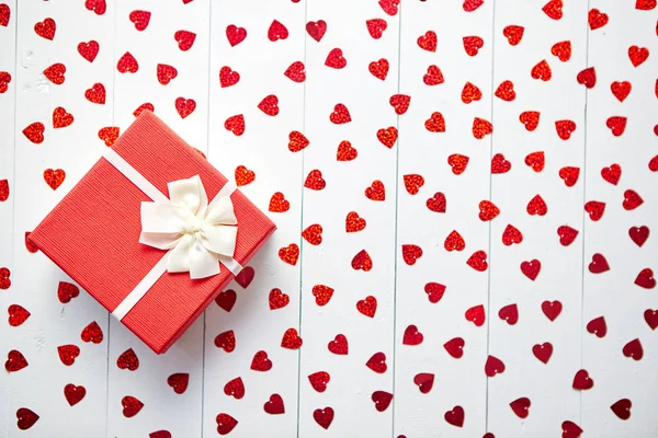 Geschenk auf herzförmigen roten Pailletten auf weißem Holztisch — Stockfoto