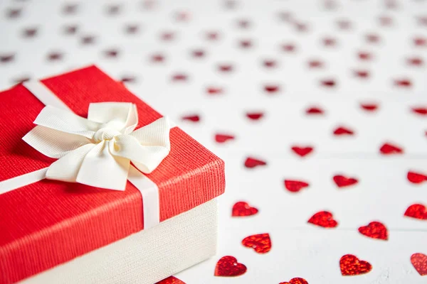 盒装礼物放置在白色木桌上的心形红色亮片 — 图库照片