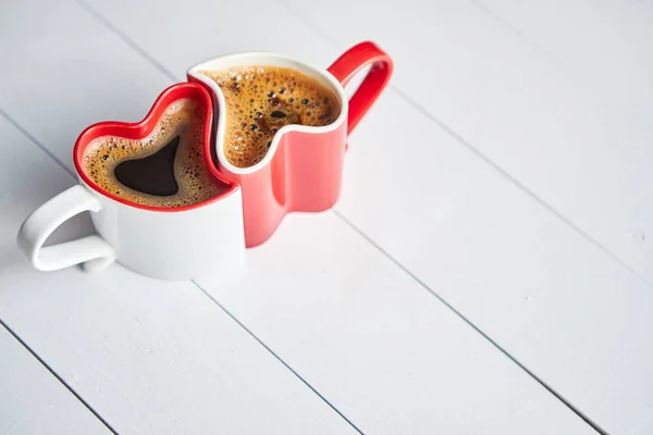 Dos tazas de café en forma de corazón conectados entre sí . — Foto de Stock