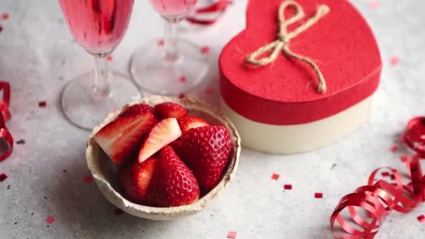 Flaska rosa champagne, glas med färska jordgubbar och hjärtformade present — Stockvideo