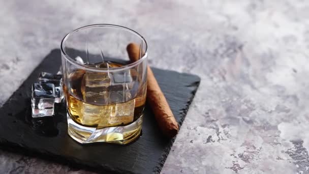 Sklenici whisky s kostkami ledu a doutník — Stock video