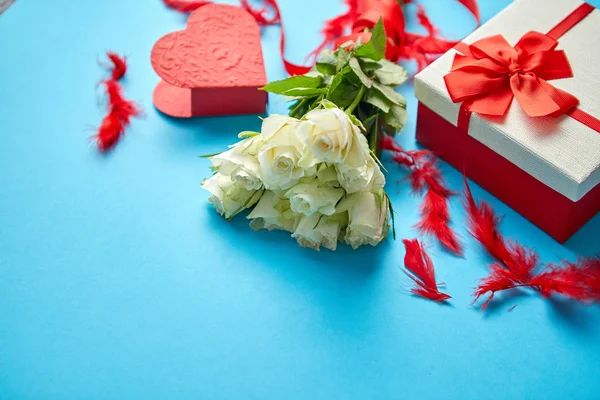 Buquê de rosas brancas com arco vermelho sobre fundo azul. Presente em caixa no lado — Fotografia de Stock