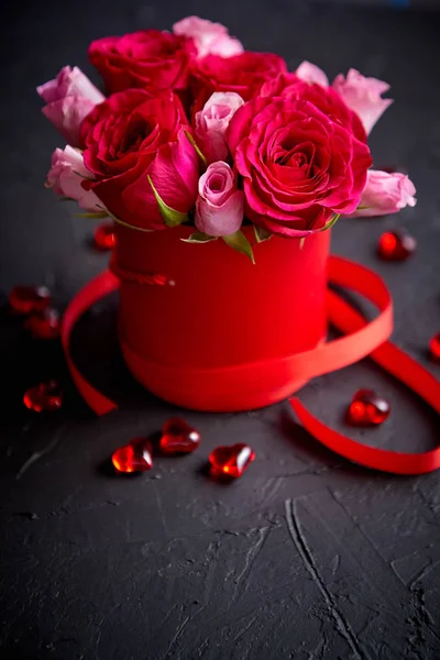 Μπουκέτο με τριαντάφυλλα συσκευάζονται στο κόκκινο κουτί και τοποθετούνται σε μαύρο φόντο πέτρα — Φωτογραφία Αρχείου