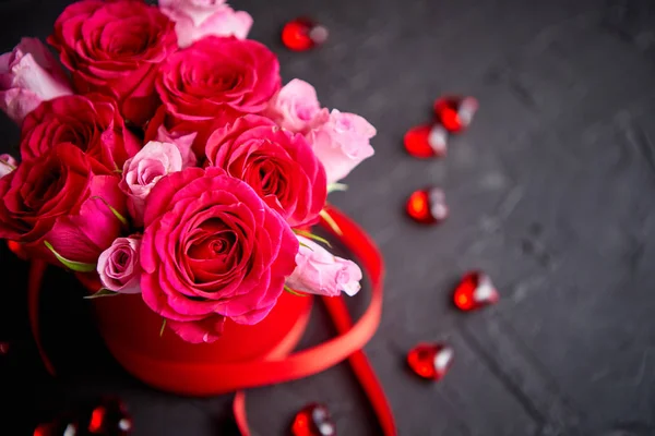 Kytice růžových růží balené v červeném poli a umístěna na černém pozadí kamene — Stock fotografie