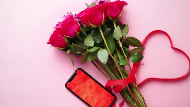 Buquê de rosas rosa com arco em forma de hart e telefone celular com tela de espaço de cópia — Vídeo de Stock