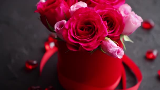 Букет з рожевих троянд упакований у червону коробку і розміщений на фоні чорного каменю — стокове відео