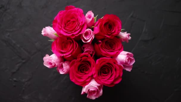 Roze rozen boeket verpakt in rood kader en geplaatst op de zwarte stenen achtergrond — Stockvideo