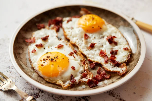 Zwei frische Spiegeleier mit knusprigem Speck auf rustikalem Teller — Stockfoto