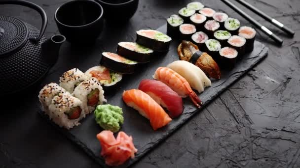 Сет суши с лососем и тунцом подают на доске из черного камня — стоковое видео