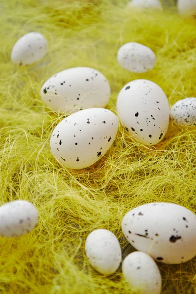 Άσπρα αυγά του Πάσχα με φακίδες τοποθετείται στο σανό, κίτρινο. — Φωτογραφία Αρχείου