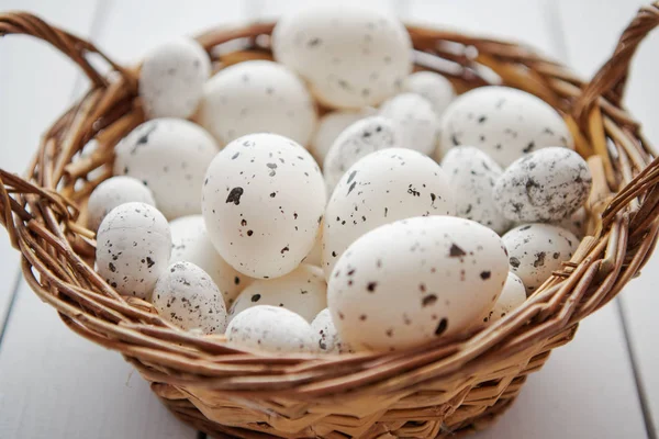 Καλάθι με λευκό διάστικτη Πασχαλινά αυγά σε καφέ ψάθινο καλάθι — Φωτογραφία Αρχείου