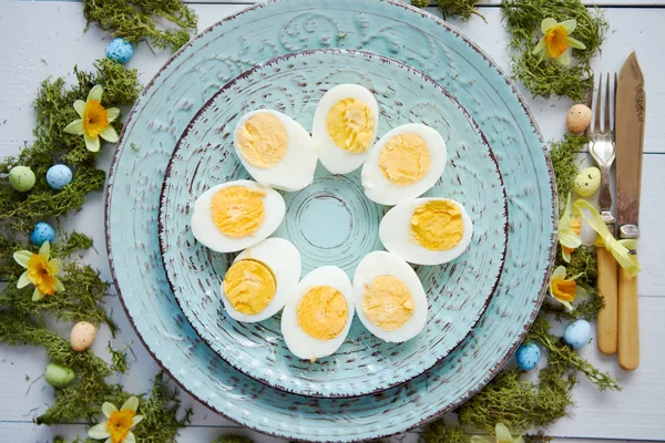 Пасхальный стол с цветами и яйцами. Декоративные тарелки с вареными яйцами — стоковое фото