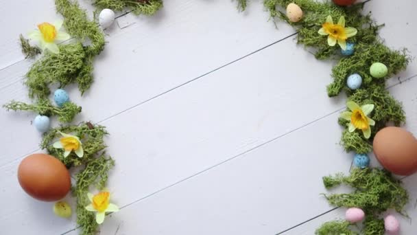 Couronne d'oeufs de Pâques décoratifs colorés sur fond de table en bois blanc — Video