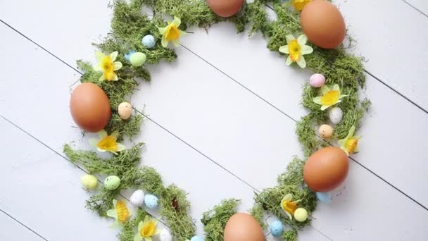 Красочные декоративные пасхальные яйца венок на белом деревянном фоне стола — стоковое видео