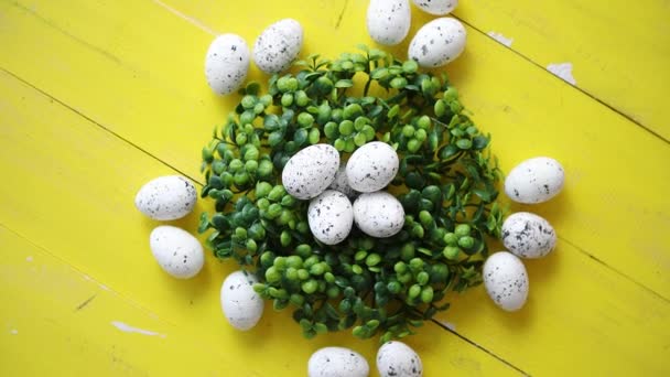 Groene decoratieve Pasen kwartel eieren krans op gele houten tafel — Stockvideo