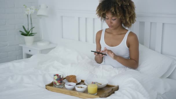 Γοητευτική γυναίκα χρησιμοποιώντας τηλέφωνο ενώ έχοντας πρωινό — Αρχείο Βίντεο