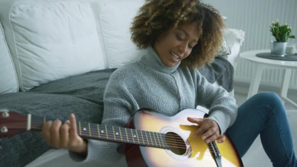 Mujer joven tocando la guitarra en casa — Vídeos de Stock