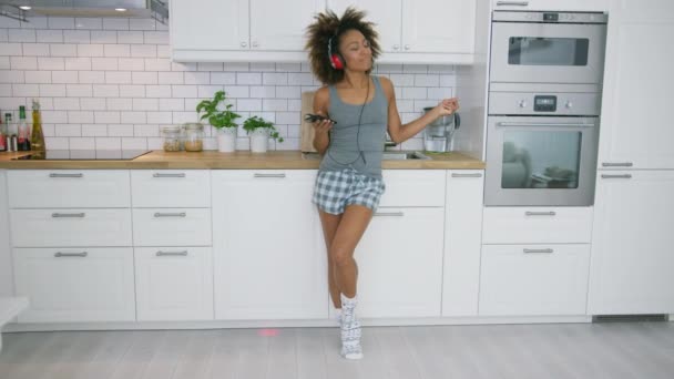 Девушка танцует на кухне со смартфоном — стоковое видео