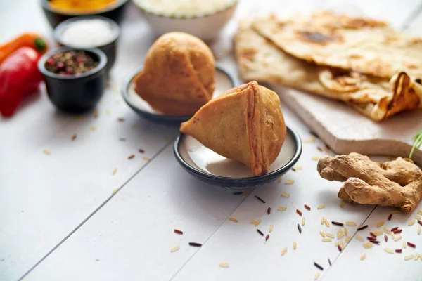 Snack traditionnel indien Samosa servi dans une assiette sur une table en bois blanc — Photo