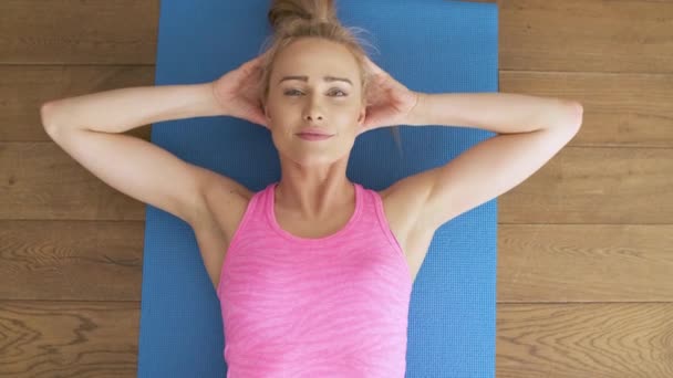 Fitness determinada mulher de meia-idade deitada fazendo crunches em casa no tapete do ginásio — Vídeo de Stock