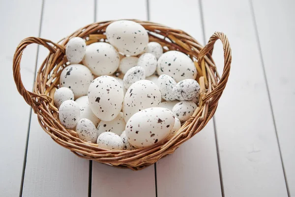 Καλάθι με λευκό διάστικτη Πασχαλινά αυγά σε καφέ ψάθινο καλάθι — Φωτογραφία Αρχείου
