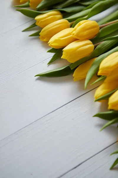 Рядок свіжих жовтих тюльпанів на білому дерев'яному столі — стокове фото