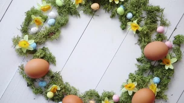 Corona de huevos de Pascua decorativa colorida sobre fondo de mesa de madera blanca — Vídeo de stock