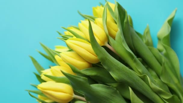 Праздничные украшения с пасхальными яйцами и желтыми тюльпанами над синим — стоковое видео