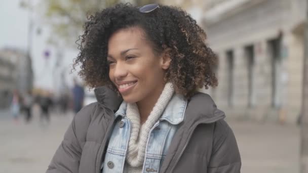 Menina bonita com corte de cabelo afro sentado no banco na rua da cidade — Vídeo de Stock