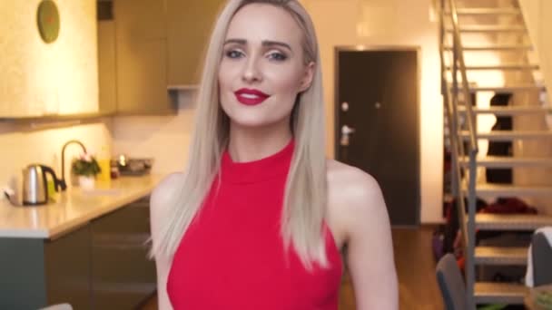 Mulher loira elegante elegante em casa sala de estar, vestindo vestido sexy vermelho — Vídeo de Stock