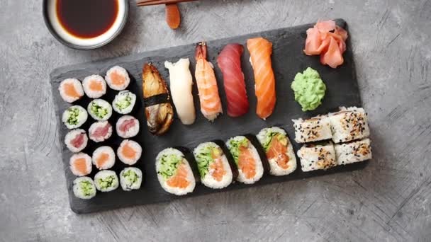 Composición de diferentes tipos de rollos de sushi colocados en tablero de piedra negro — Vídeos de Stock