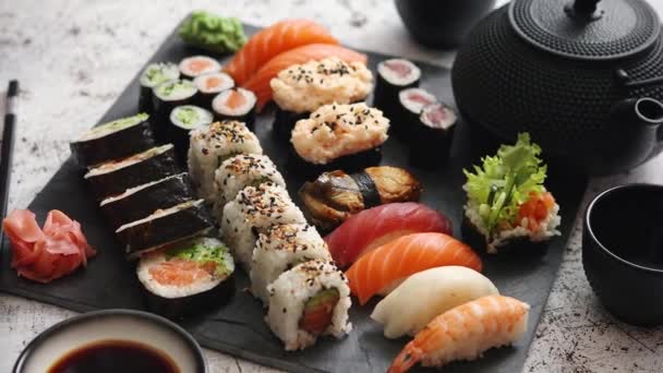 Sortimento de diferentes tipos de rolos de sushi colocados na placa de pedra preta — Vídeo de Stock