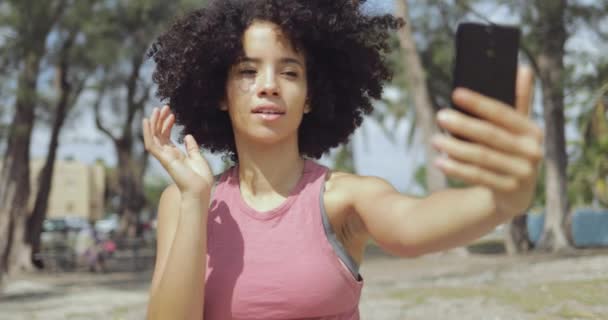 Lachendes junges Mädchen macht Selfie im Park — Stockvideo