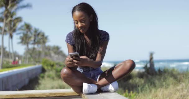 Beautiful woman using phone on fence — Stock Video