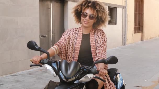 Современная этническая женщина, сидящая на скутере на улице — стоковое видео